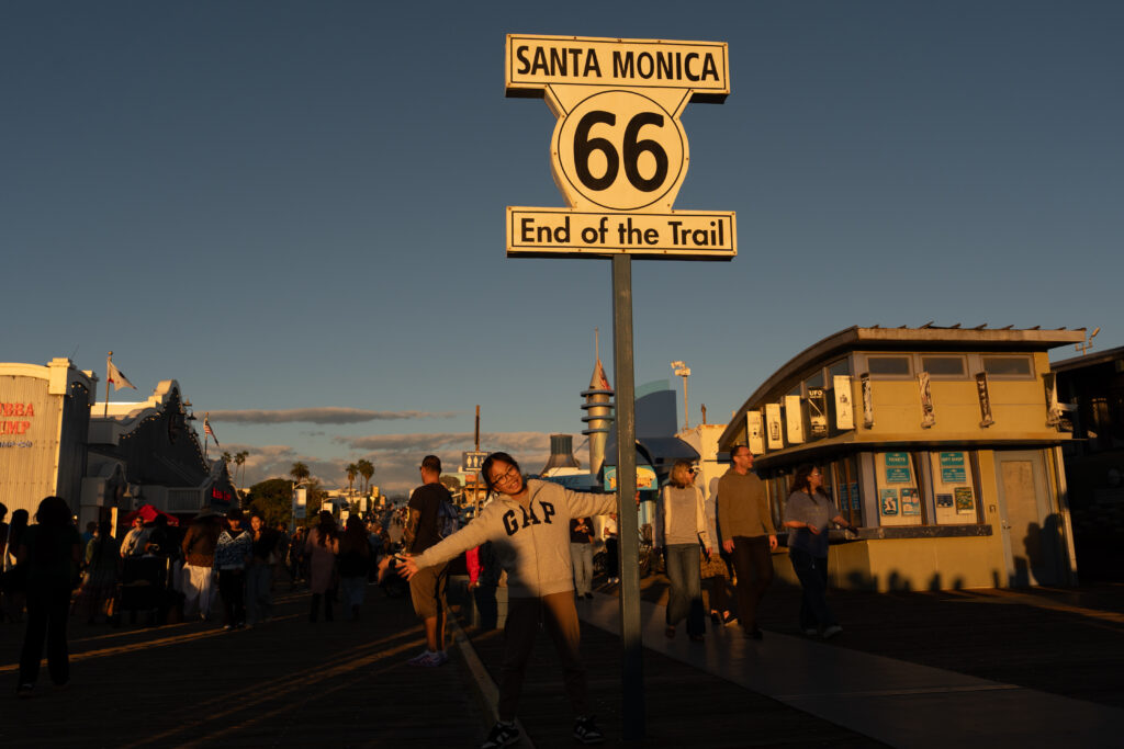 FILE - A visitor poses for photos with the "End of the Trail" Route 66 sign on the Santa Monica Pier in Santa Monica, Calif., Saturday, Nov. 22, 2025. (AP Photo/Jae C. Hong, File)