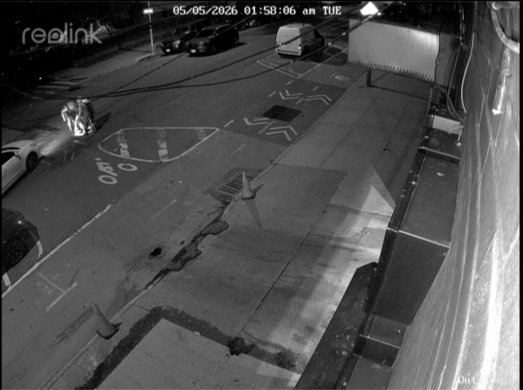 In this image from a surveillance video provided by AKI AUTO CARE, three people descend into a sewer on a street in New York, on May 5, 2026. Photo: AKI AUTO CARE via AP