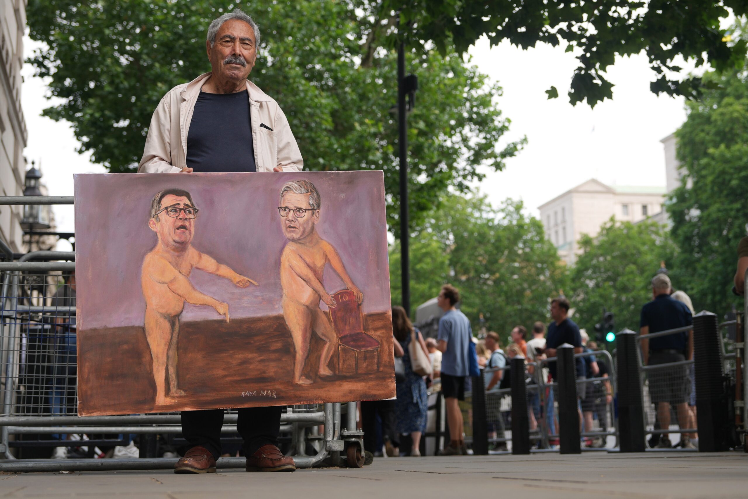 Artist Kaya Mar shows his newest painting outside Downing Street after Britain's Prime Minister Keir Starmer announced his resignation in London, Monday, June 22, 2026. Photo: Alastair Grant/AP
