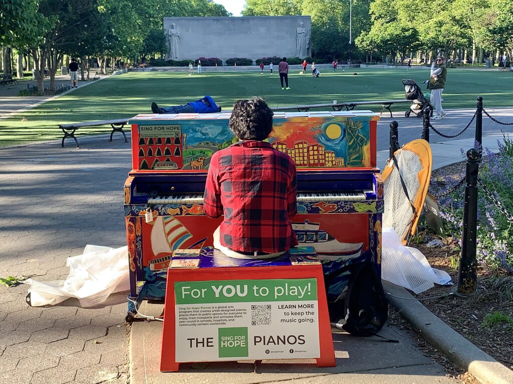 A park-goer on Saturday played the "I Am Not Broken" Sing for Hope piano in Cadman Plaza Park’s Juneteenth Grove. The piano was painted by students with the Red Hook Art Project. Photo: Mary Frost/Brooklyn Eagle